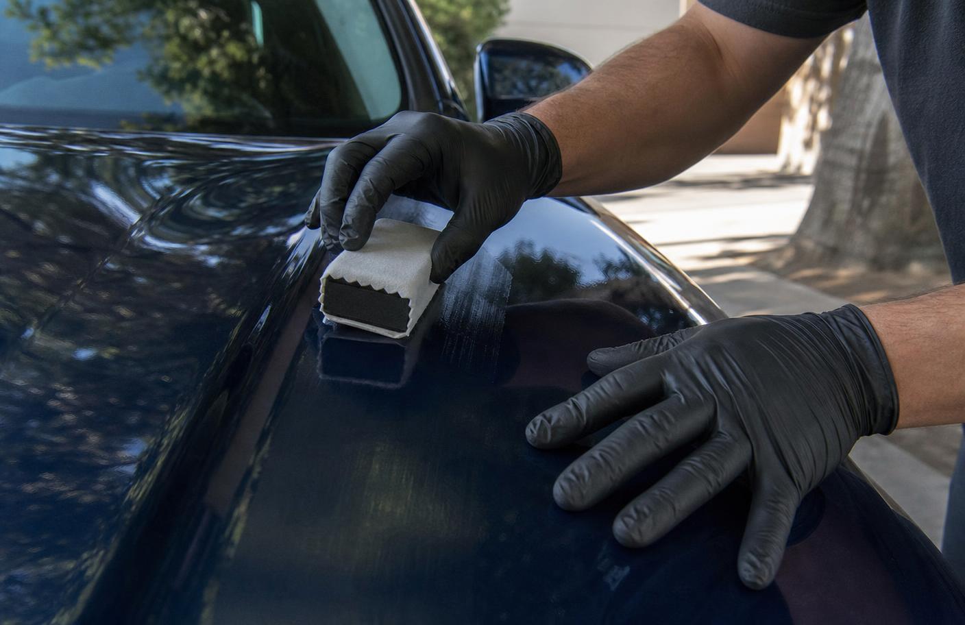 Detailer applying ceramic coating to a blue car fender with a suede applicator block