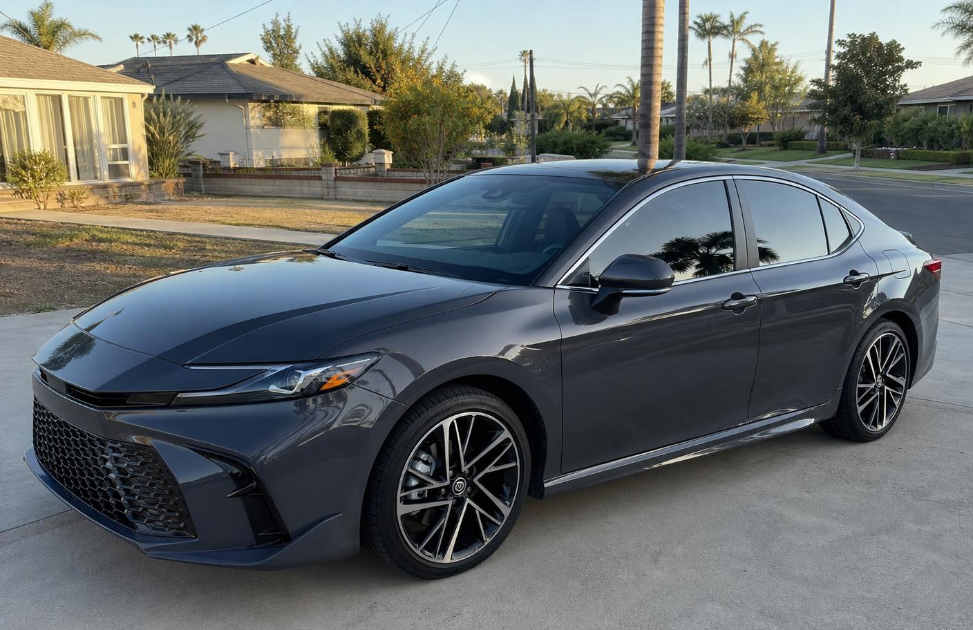 Freshly corrected dark grey sedan with sharp clean reflections parked in a Los Angeles driveway in late afternoon light
